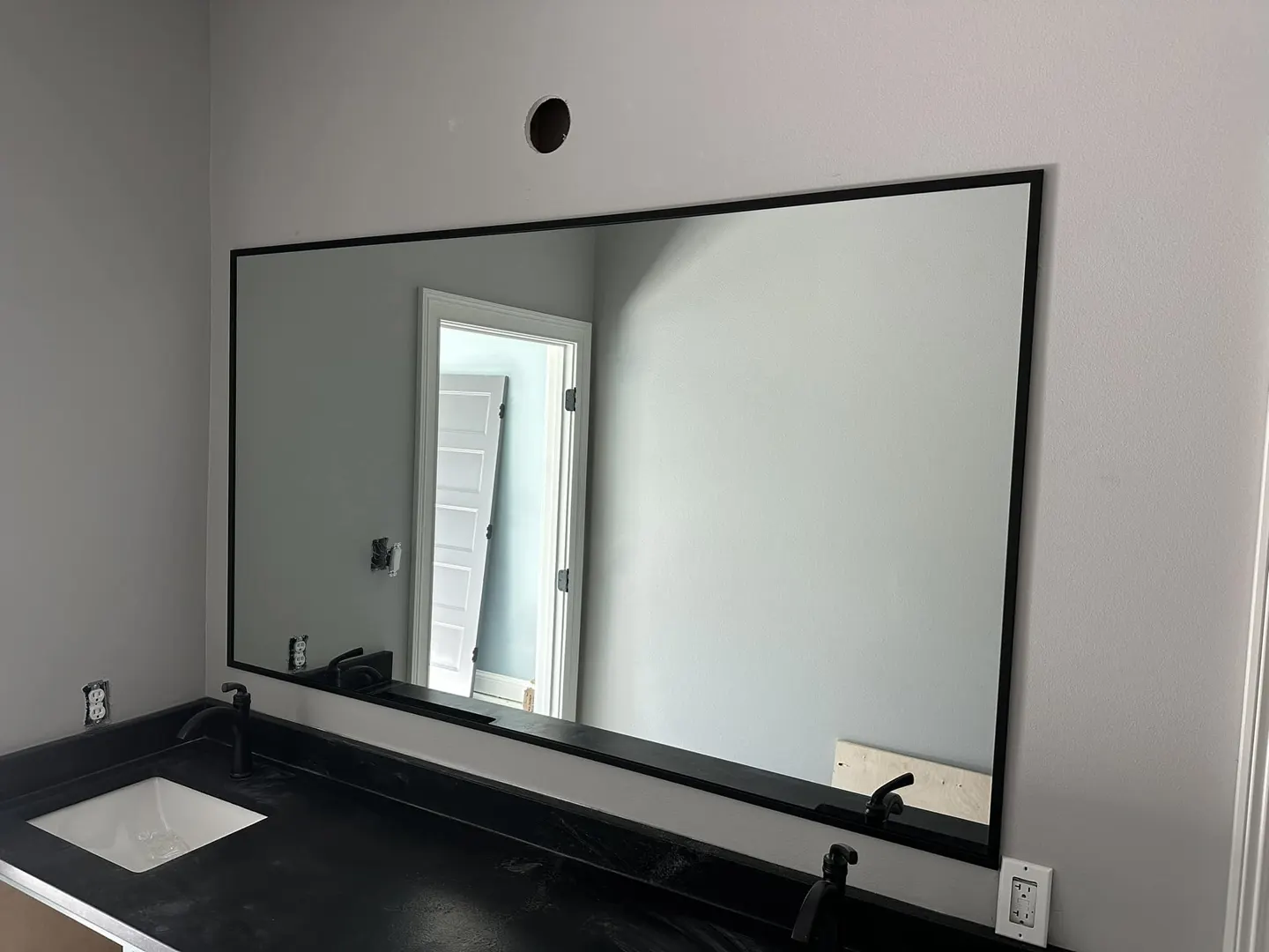 Large mirror with a slim dark frame above a vanity
